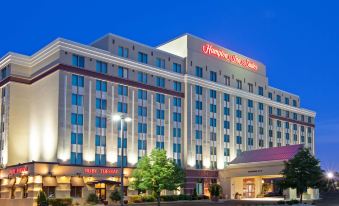 a large hotel building surrounded by trees and a parking lot , with the sun setting in the background at Hampton Inn & Suites Chicago-North Shore/Skokie