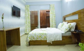 a well - lit bedroom with a wooden bed , white bedding , and curtains , as well as a tv on the wall at Hotel Lewi
