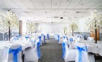 a large banquet hall is set up for a wedding reception , with tables covered in white tablecloths and chairs arranged around them at Holiday Inn Leeds - Wakefield M1, Jct.40