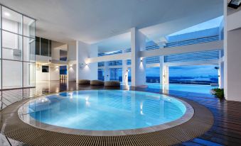 an indoor swimming pool with a circular design and multiple windows overlooking the ocean , creating a serene atmosphere at Fraser Place Puteri Harbour, Johor