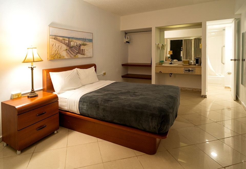 a large bed with a wooden headboard and white pillows is in a room with a painting on the wall at Solace by the Sea