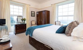 a large bedroom with a king - sized bed , two windows , and a dresser near the window at Ees Wyke Country House