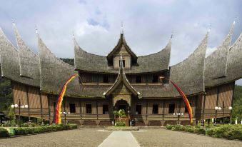 a large wooden building with multiple flags flying in front of it , possibly at a convention or event at Novotel Bukittinggi