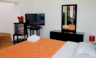 a modern bedroom with an orange bedspread , black furniture , and a television on a wooden table at Hotel Casablanca