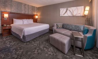 a hotel room with a king - sized bed , a couch , and a tv . the room is well - lit and appears to be clean at Sonesta Select Columbia