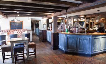 a modern bar with wooden beams , blue and red interior , and white furniture , including a dining table and chairs at Premier Inn Northwich (Sandiway)