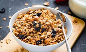 a white bowl filled with granola and topped with cherries sits on a wooden cutting board at The Headwaters Eco Lodge