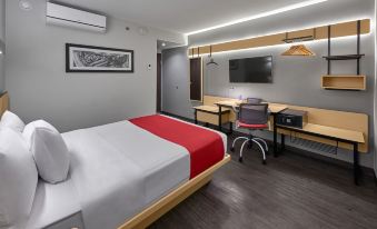 a modern hotel room with a red and white bed , a desk , and a chair at City Express by Marriott Cdmx la Villa