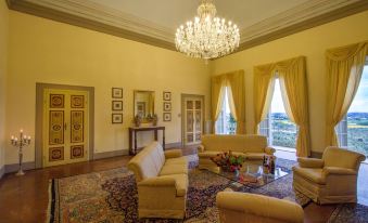 a large , elegant living room with yellow walls , a chandelier , and multiple couches and chairs arranged around a coffee table at Villa Alta - Residenza d'Epoca Con Piscina
