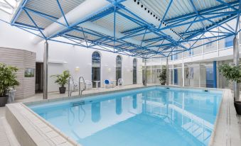 an indoor swimming pool with a blue and white color scheme , surrounded by a white building at Hotel Norden