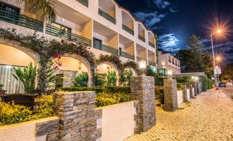 a row of buildings with stone pillars and greenery , illuminated by lights at night , near a cobblestone walkway at Casablanca Unique Hotel