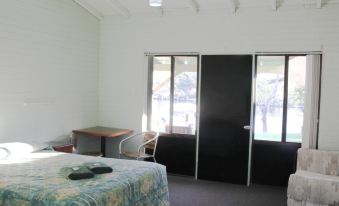 a bedroom with a bed , desk , and sliding glass doors leading to an outdoor area at Ravenswood Hotel