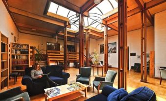 a woman is sitting on a couch in a spacious room with wooden floors and high ceilings at Royal Maritime Hotel