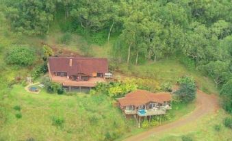 aerial view of a large house surrounded by trees and grass , with a car parked nearby at Adventure in Paradise