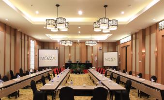 a conference room set up for a meeting with rows of chairs and tables , along with two large screens on the walls at Swiss-Belinn Timika