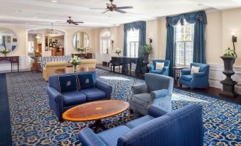 a spacious living room with blue couches , chairs , and a dining table in the background at Historic Boone Tavern
