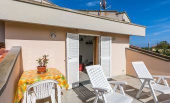 a rooftop patio with several white lounge chairs and a dining table , creating a comfortable outdoor seating area at Mansarda