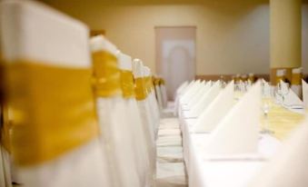 a row of white tablecloths with gold trim , arranged in rows on a long table at Hotel Grand