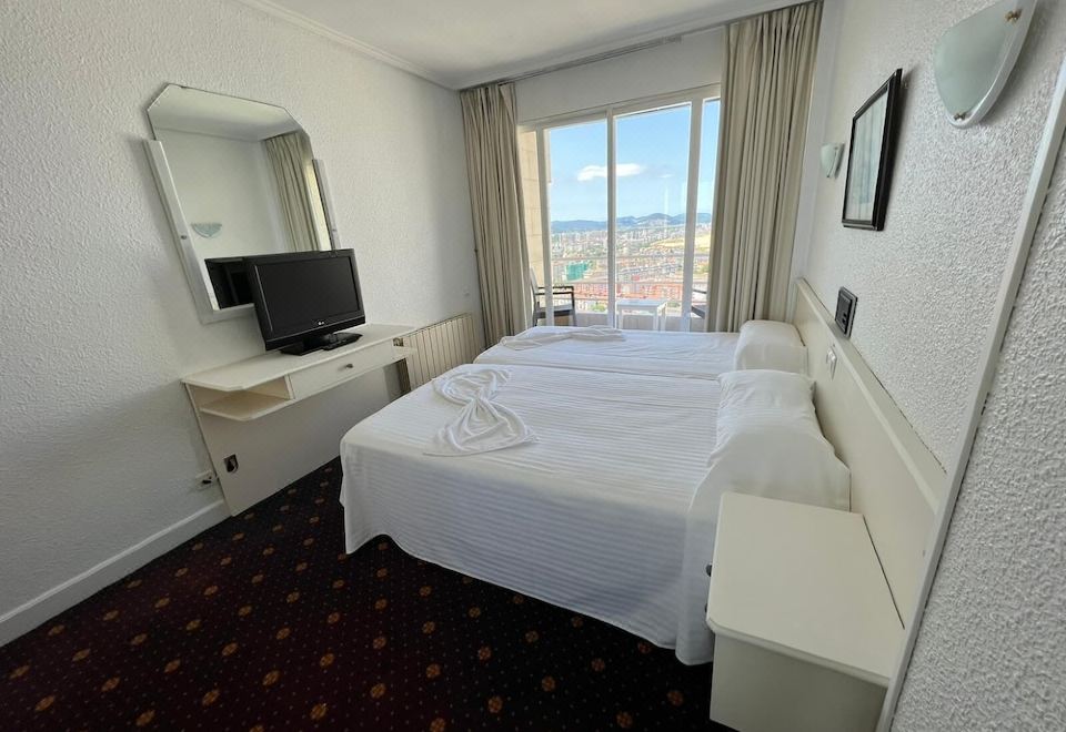 a hotel room with a white bed , a television , and a window overlooking the city at Hotel Miramar Laredo