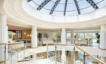 a grand foyer with a glass ceiling , large windows , and a staircase leading up to the second floor at Iberostar Selection Creta Marine