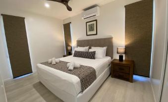 a large bed with white linens and a leopard print blanket is in a bedroom with wooden floors at Island Villas