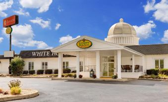 "a white building with a large dome and the words "" white hotel "" on top , surrounded by trees and grass" at Ramada by Wyndham Richland Center