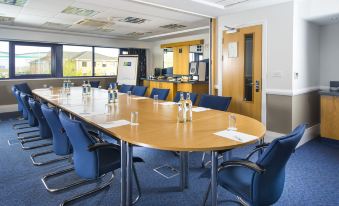 a conference room with a large table surrounded by chairs , and several bottles of water on the table at Holiday Inn Express Northampton - South