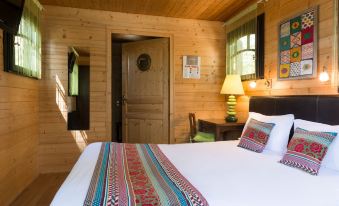a cozy wooden cabin bedroom with a large bed , a dresser , and a door leading to another room at Auberge la Tomette, the Originals Relais
