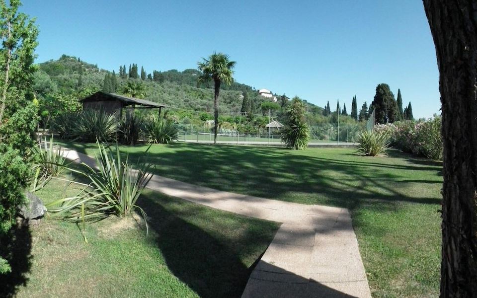 a lush green park with palm trees , a walking path , and a house in the background at Casa Matilde