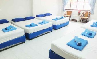 a room with four beds arranged in a row , each with a blue and white color scheme at HaadSon Resort