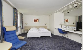 a hotel room with a bed , two chairs , and a desk , all situated in a white - walled room at Hotel Norden