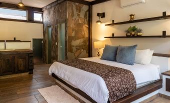 a cozy bedroom with a large bed , hardwood floors , and a stone wall decorated with lights at Las Jaras Aguas Termales