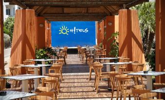 a restaurant with wooden tables and chairs , a blue sky with the sun logo , and potted plants at Ohtels Cabogata