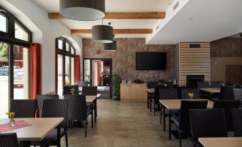 a restaurant with wooden tables and chairs , a large screen on the wall , and pendant lights at Hotel Albatros