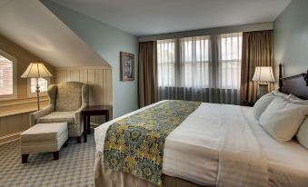 a large bed with a floral blanket is situated in a hotel room next to a window at The Inn at Wise