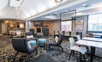 a modern living room with various seating options , including couches , chairs , and ottomans , arranged around a fireplace at Residence Inn by Marriott Princeton at Carnegie Center