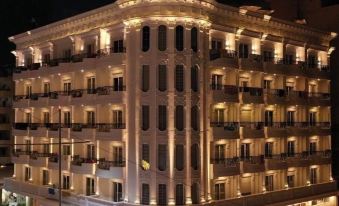 a large , ornate hotel building with multiple floors and balconies lit up at night , creating a warm and inviting atmosphere at Hotel Empire Albania