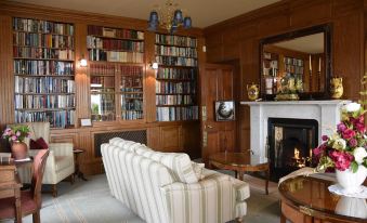 a cozy living room with a couch , a fireplace , and a bookshelf filled with books at Pool House