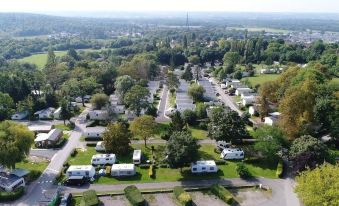 aerial view of a residential area with multiple rvs parked in a lot , surrounded by trees and buildings at Camping le Parc de Paris