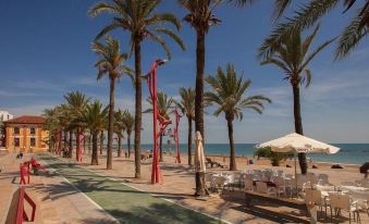 a tropical beach with palm trees , a white umbrella , and lounge chairs under a clear blue sky at Estudios RH Vinaros