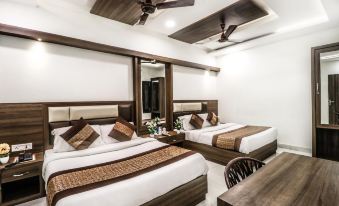 a hotel room with two beds , a desk , and a ceiling fan , all decorated in white and brown at Hotel Kings