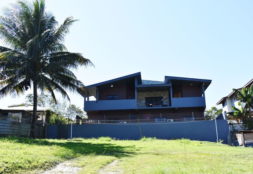 a large , modern house surrounded by grass and trees , with a palm tree in the background at Lucina's