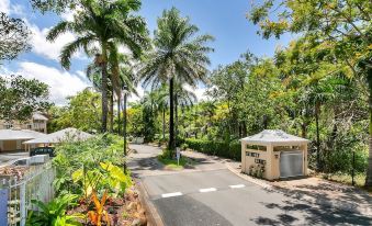 a paved road surrounded by lush green trees and bushes , with a gazebo on the side at Trinity Links Resort