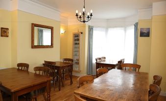 a dining room with wooden tables and chairs arranged for a group of people to sit and eat at Acorns Guest House