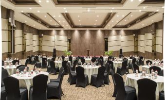a large banquet hall filled with round tables and chairs , ready for a formal event at Hotel Horison Gkb Gresik