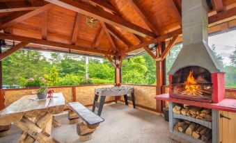 an outdoor dining area with a wooden table and benches , a fire pit , and a fireplace at Tina