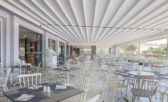 an empty restaurant with white tables and chairs under a white ceiling , creating a modern and clean atmosphere at Atali Grand Resort