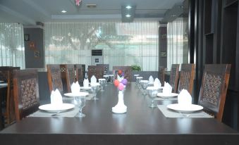 a long dining table set with white plates , silverware , and wine glasses in a restaurant at Griya Hotel