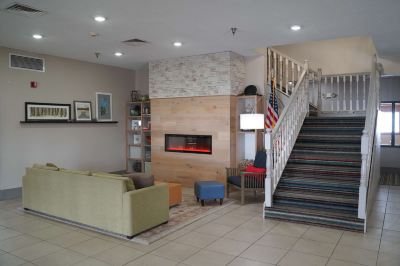 a modern hotel lobby with a fireplace , couches , and stairs leading to the upper floors at Country Inn & Suites by Radisson, Watertown, SD