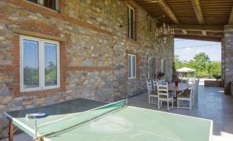a ping pong table is set up in a covered outdoor area with stone walls and large windows at Celeste